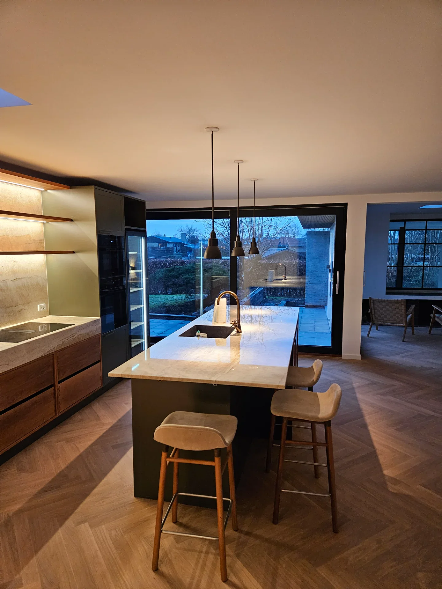 Moderne køkken med ø-område, store vinduer og elegant design.