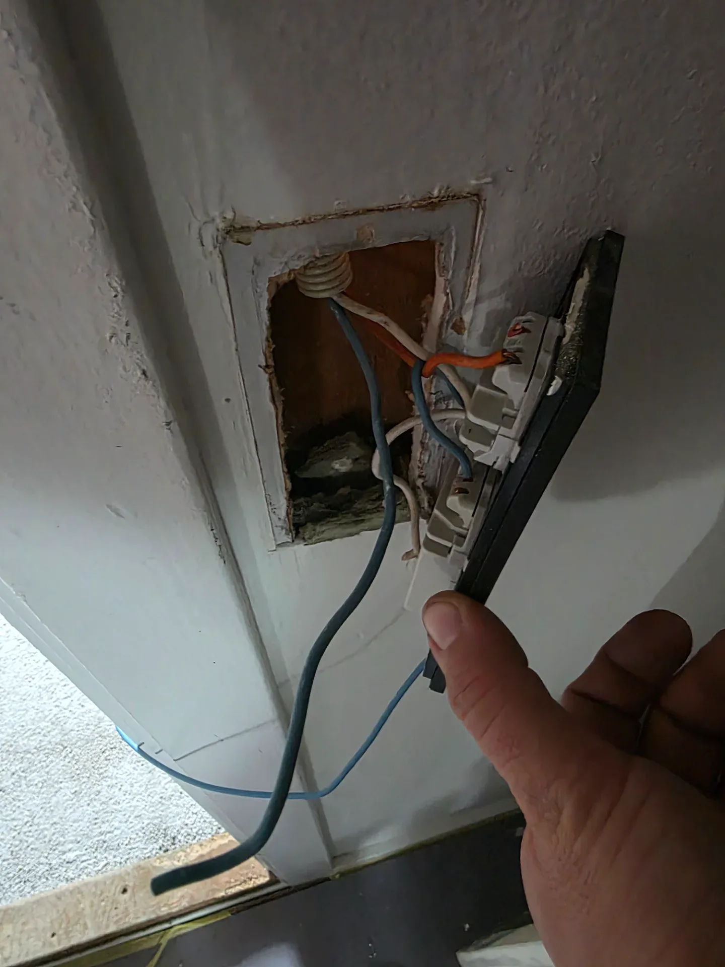 Elektrisk vægudtag med kabelføring under installation.