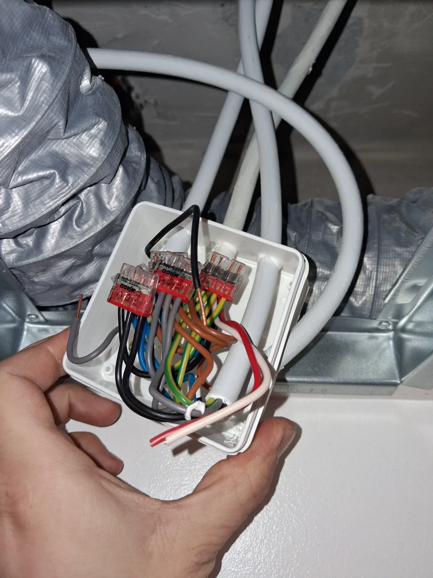 Elektrisk installation med ledninger og sikringer i et vægudtag.