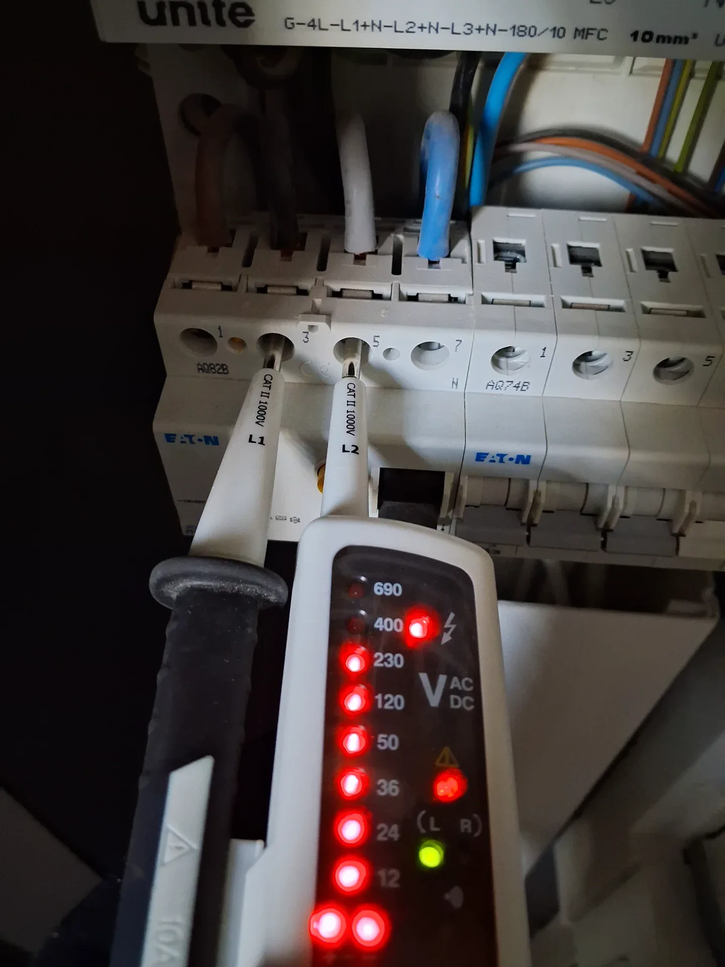 Elektrisk overvågningsenhed med LED-lys, tilsluttet elektriske kredsløb, viser spænding og status.