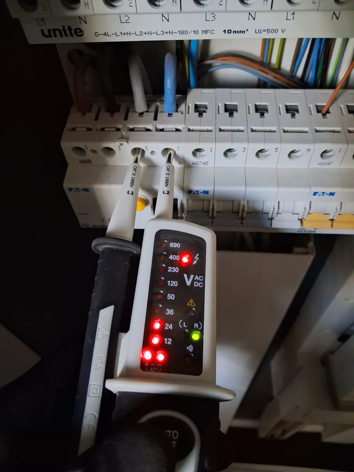 Elektriker tester elektrisk kredsløb med multimeter i el-tavle.