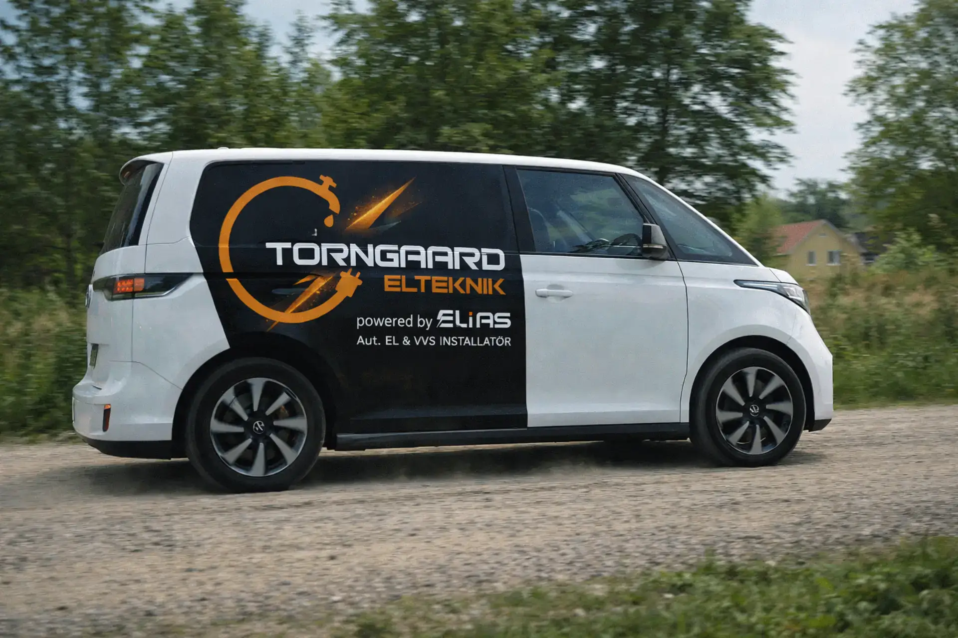 Elektrikerbil med Torngaard ElTeknik logo og tekst, kører på vej.